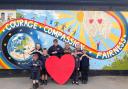 Morda pupils are pictured holding their Morda 'big heart' in front of the school's  'Morda Values' rainbow mural. (Left to right: Macy Jones, Cara Laing, Tomas Counsell, Charlie Beaton, Millie Barton, Ella Evans, Charlie Weaver and Edward Vaughan.)