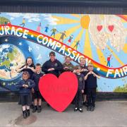 Morda pupils are pictured holding their Morda 'big heart' in front of the school's  'Morda Values' rainbow mural. (Left to right: Macy Jones, Cara Laing, Tomas Counsell, Charlie Beaton, Millie Barton, Ella Evans, Charlie Weaver and Edward Vaughan.)