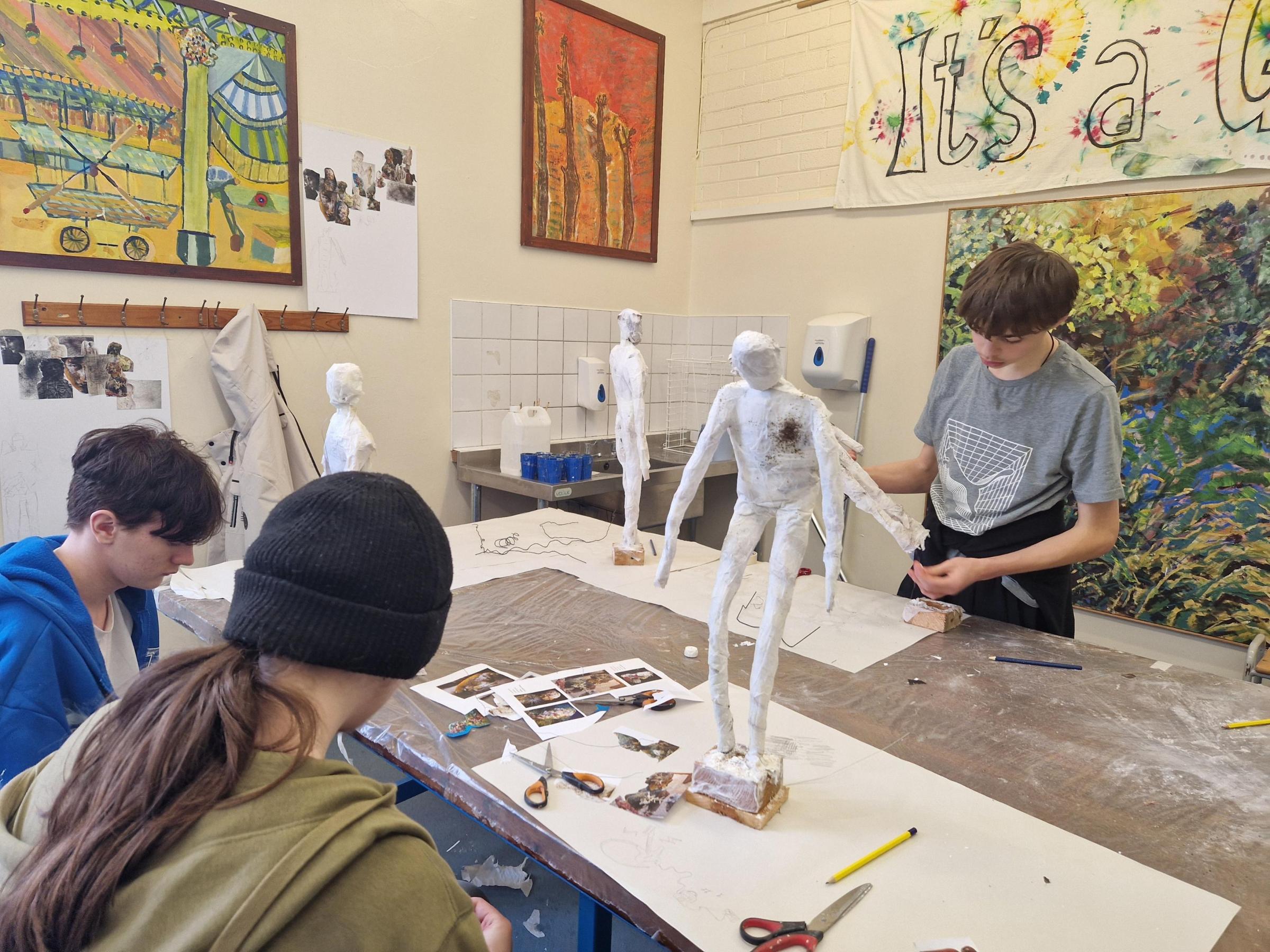 Students Harvey, Joshua, and Harry work on their fallen angel sculptures.